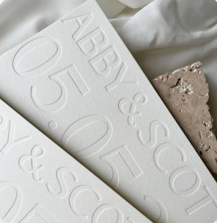 Debossed lettering pressed below the surface of white stationery.